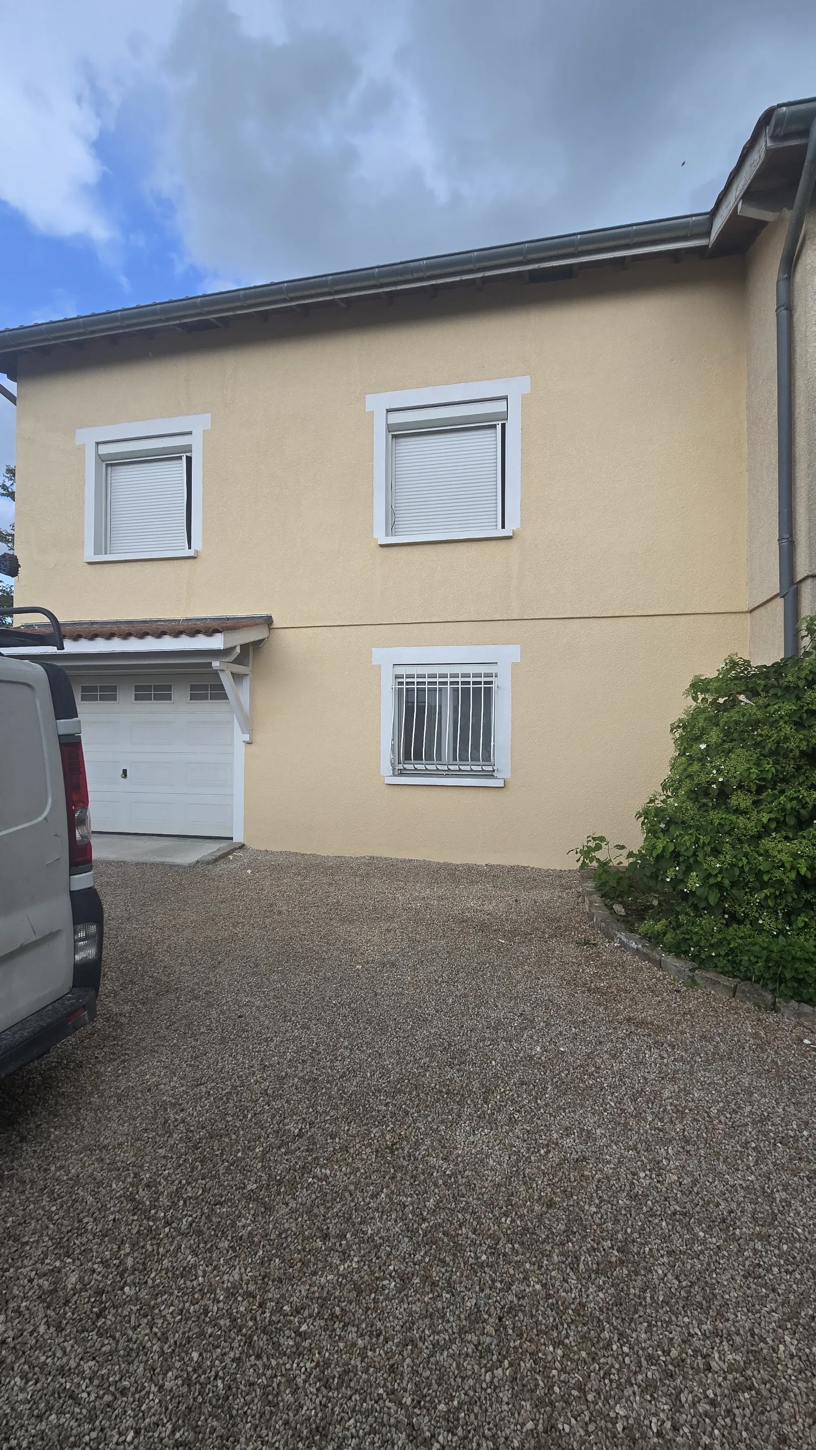 Façade ocre repeinte avec encadrements de fenêtres blancs nets